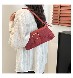 Detail of red faux leather shoulder bag with crocodile pattern and golden buckle