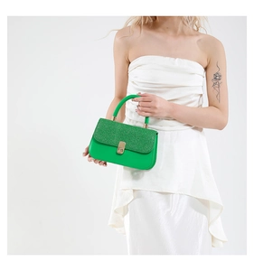 Detail of green glitter and glossy leather handbag with a gold metal clasp