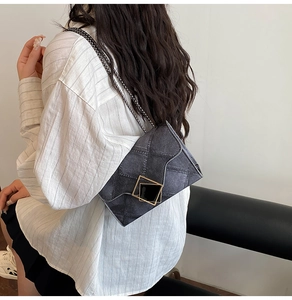 Detail of blue denim shoulder bag with quilted stitching and gold square buckle