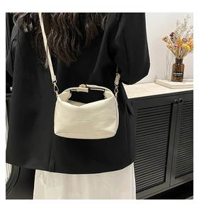 Detail of a chic cream-colored patchwork crossbody bag with elegant gold metal clasp