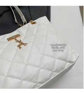 Detail of white quilted leather tote bag featuring a golden deer charm and metal hardware