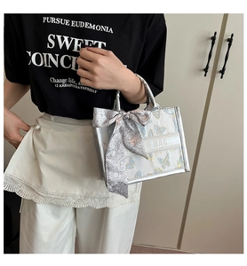 Detail of silver canvas tote with light blue butterfly embroidery and grey silk bow tie