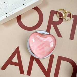 Pink heart-shaped phone grip with marble texture and high-gloss finish on a circular base