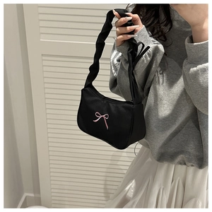Detail of a black shoulder bag featuring pink bow embroidery and a ruched cloud handle