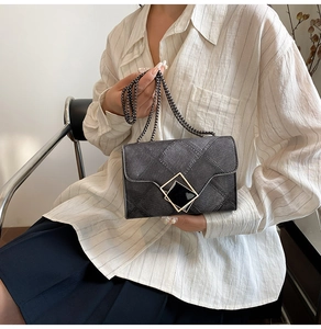 Detailed view of dark grey crossbody bag with geometric buckle and black chain strap