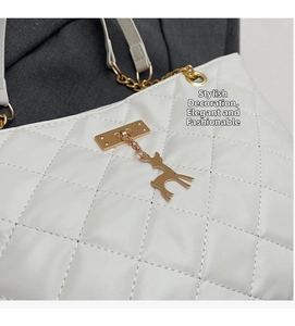 Close-up of white quilted leather bag featuring a gold deer charm and chain strap detail