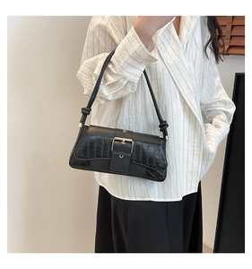 Close-up of black crocodile pattern baguette bag featuring high-shine gold buckle detail