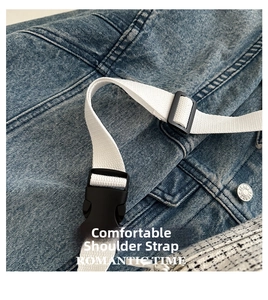 Detail of blue washed denim bag with adjustable white woven strap and black plastic buckle