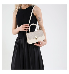 Detail of minimalist cream crossbody bag featuring a glitter flap and gold twist lock clasp
