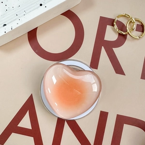 Pink and orange gradient heart phone socket grip with glossy finish on a minimalist base