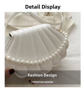 Détail du sac à main en forme de coquillage avec surpiqûres et poignée en perles