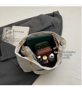 Detail of spacious interior in white quilted chain tote bag holding daily essentials