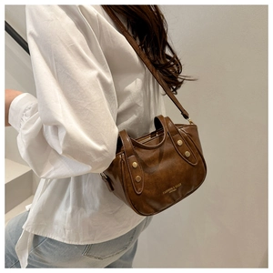 Detailed macro view of dark brown leather bucket bag with golden rivet side accents