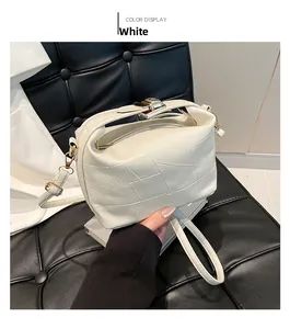 Close-up of white leather square bag with geometric patchwork and gold clasp hardware