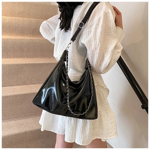 Detail of glossy black hobo bag with silver chain strap and polished faux leather texture