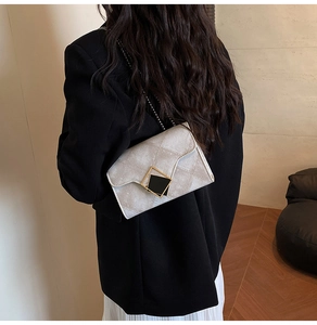 Detail of a chic gradient crossbody bag with quilted texture and gold chain on model