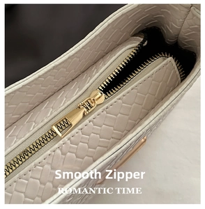 Close-up of beige woven texture underarm bag with a premium gold zipper detail