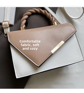 Dettaglio borsa a contrasto con manico a treccia e barra decorativa in metallo dorato