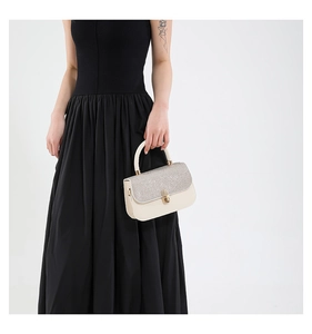 Detail of glitter flap and golden cylinder lock on ivory leather crossbody bag