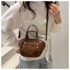 Close-up of a vintage brown leather bucket bag with gold studs and brand logo detail