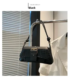 Detail of black faux crocodile leather baguette bag with gold buckle and slim strap