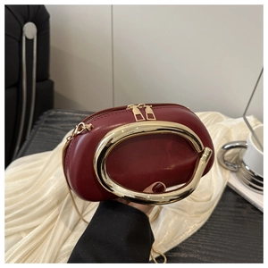 Dettaglio pochette in pelle bordeaux con manico ad anello dorato e doppia cerniera