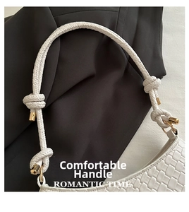 Detail of white woven leather underarm bag featuring padded handle with knot and gold metal
