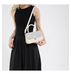 Detail showing the silver glitter flap and gold-tone metal buckle on the cream crossbody bag