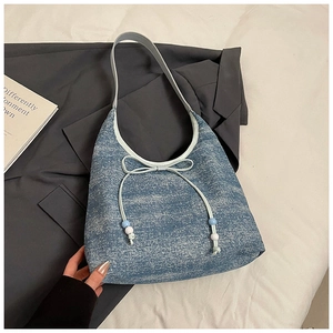 Detailansicht der hellblauen Jeansschleife mit bunten Perlen an der schicken Achseltasche