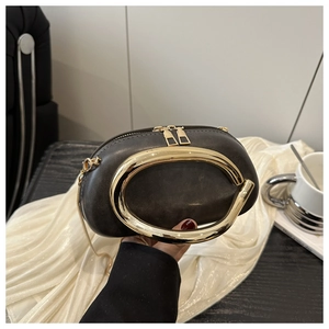 Dettaglio borsa tonda vintage con grande manico in metallo dorato e catena sottile