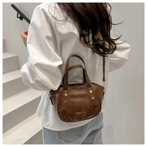 Dark brown retro leather bag shown on model featuring gold hardware and logo detail