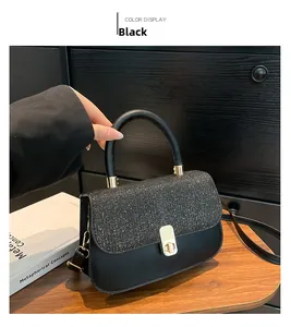 Detail of the black leather bag featuring a sequin flap and gold twist-lock closure