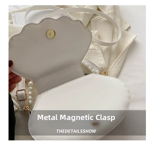 Détail d'un sac en forme de coquille avec fermoir magnétique et bandoulière en perles