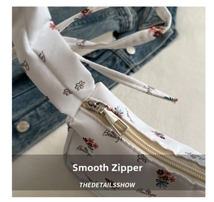 Detailansicht der weißen Handtasche mit Blumenmuster, Silberreißverschluss und Schriftzug