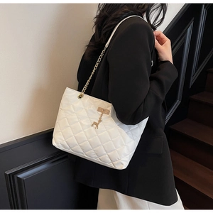 White quilted tote bag with golden chain strap and deer pendant shown on shoulder