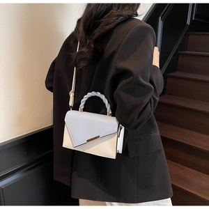 Détail du sac bicolore bleu et blanc avec poignée tressée et garniture en métal doré