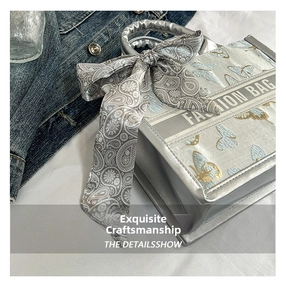 Detail of silver tote bag featuring butterfly print and paisley silk scarf handle