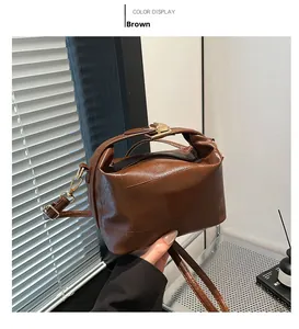 Detail of brown leather handbag with golden lock and stylish pleated top handle design
