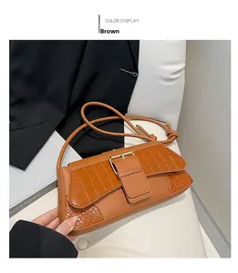 Detailed view of brown crocodile texture flap and gold buckle on stylish underarm bag