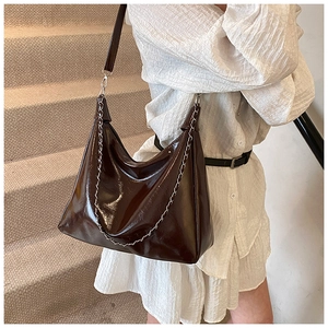 Detail of dark brown glossy patent leather shoulder bag with silver metal chain decor
