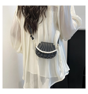 Détail du sac bandoulière noir en forme de coquillage avec perles et boucles dorées