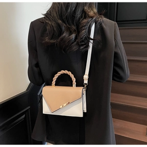 Détail d'un sac à main bicolore avec poignée tressée et accents métalliques dorés élégants