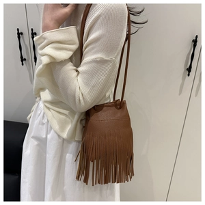 Detailed side view of a brown bucket bag with long tassels and matching leather strap