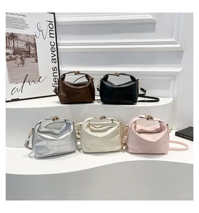 Close-up of stylish leather handbags with unique folded design and gold metal rotary locks