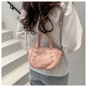 Detailed shot of pink leather bucket bag with gold studs and brand logo lettering