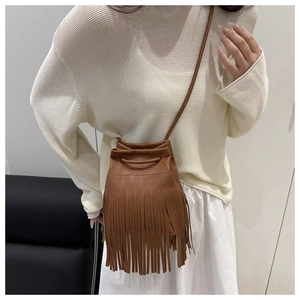 Detailed view of brown leather fringe bucket bag worn by model showing tassel texture