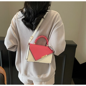 Détail du sac bandoulière bicolore avec poignée tissée rose et détails en métal doré