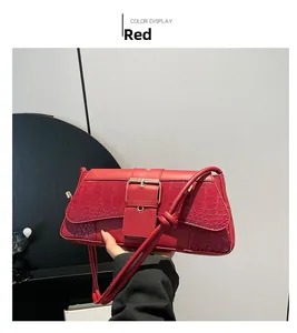 Detail of red shoulder bag featuring crocodile texture flap and gold buckle hardware