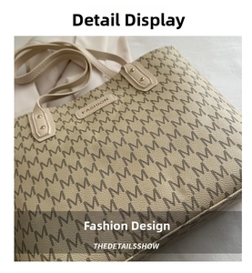 Detail of beige tote bag with M-pattern print, fashion leather tag, and gold rivets