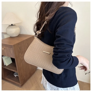 Detail of beige woven texture shoulder bag with gold metal trim and knotted strap detail